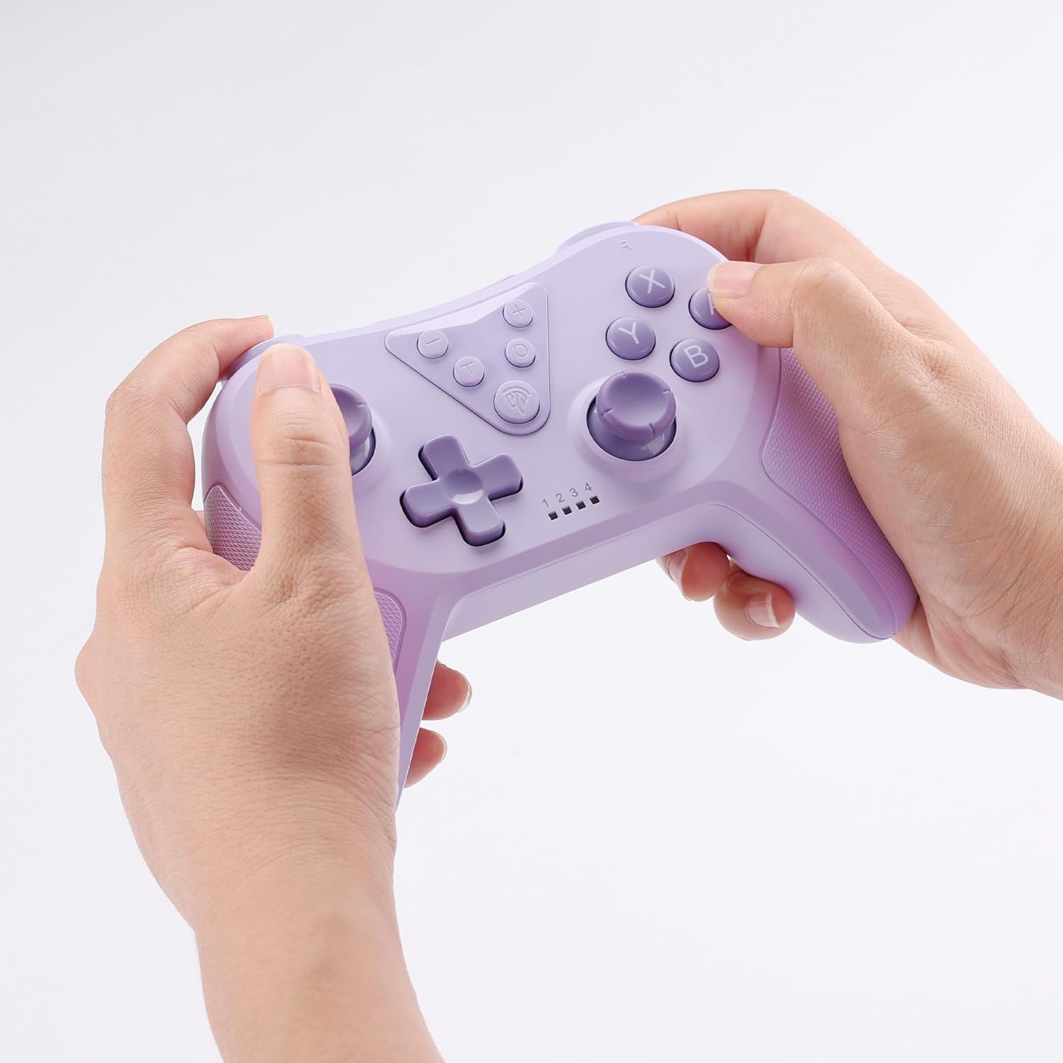 Purple gaming controller held by two hands on a light gray background