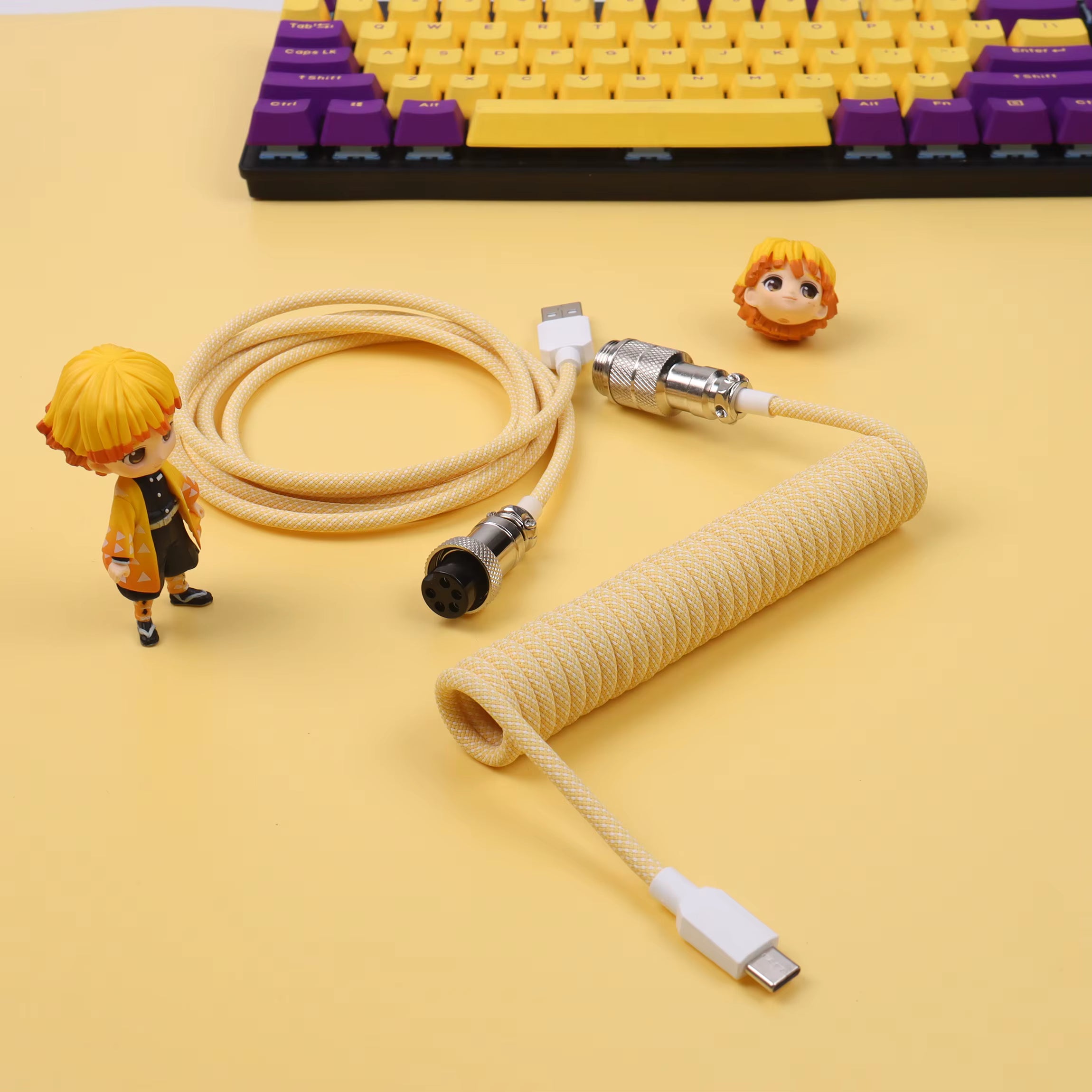 Yellow braided cable with connectors on a yellow background, featuring a small figurine.