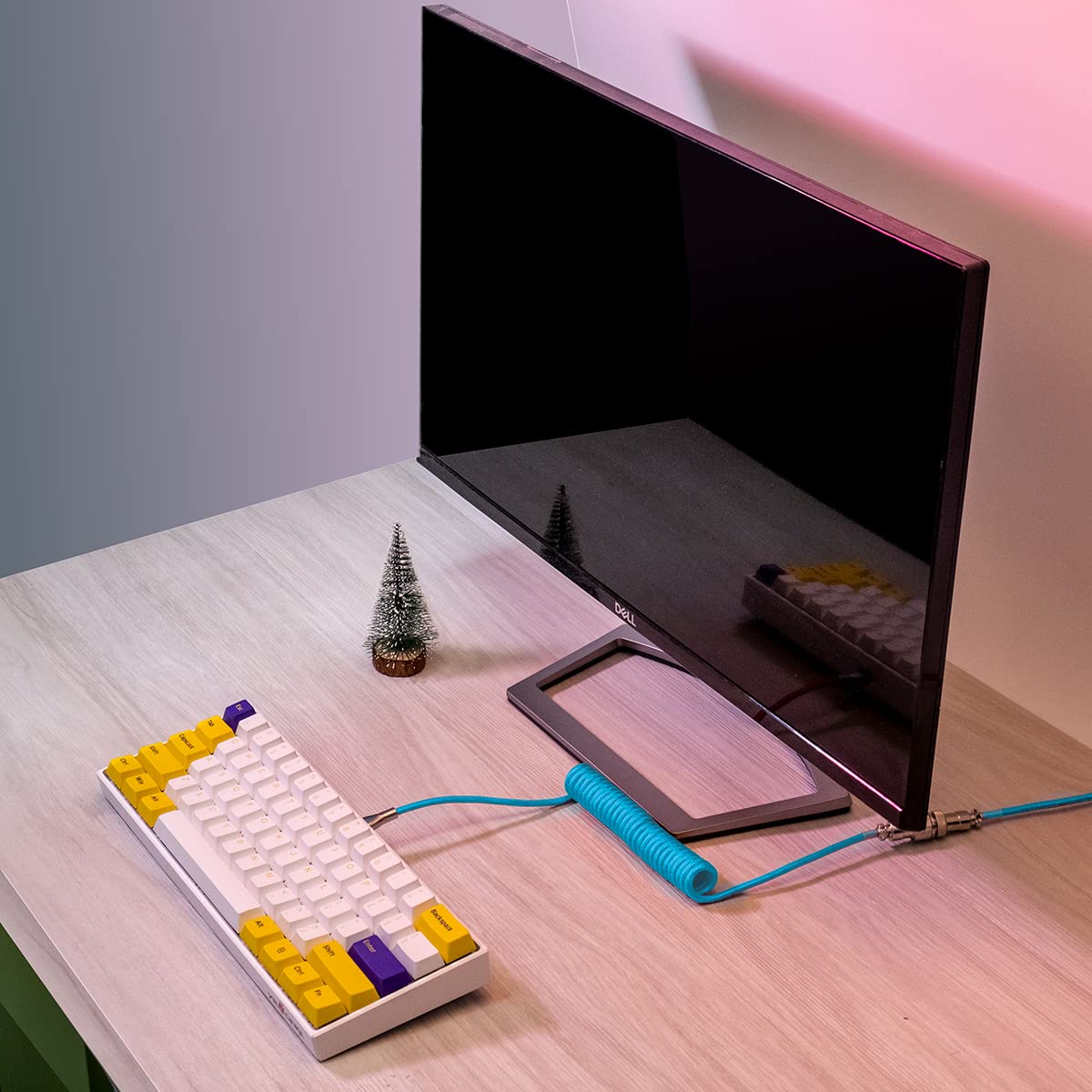 Keyboard with unique design on a desk next to a computer monitor and Macaron Coiled Cable