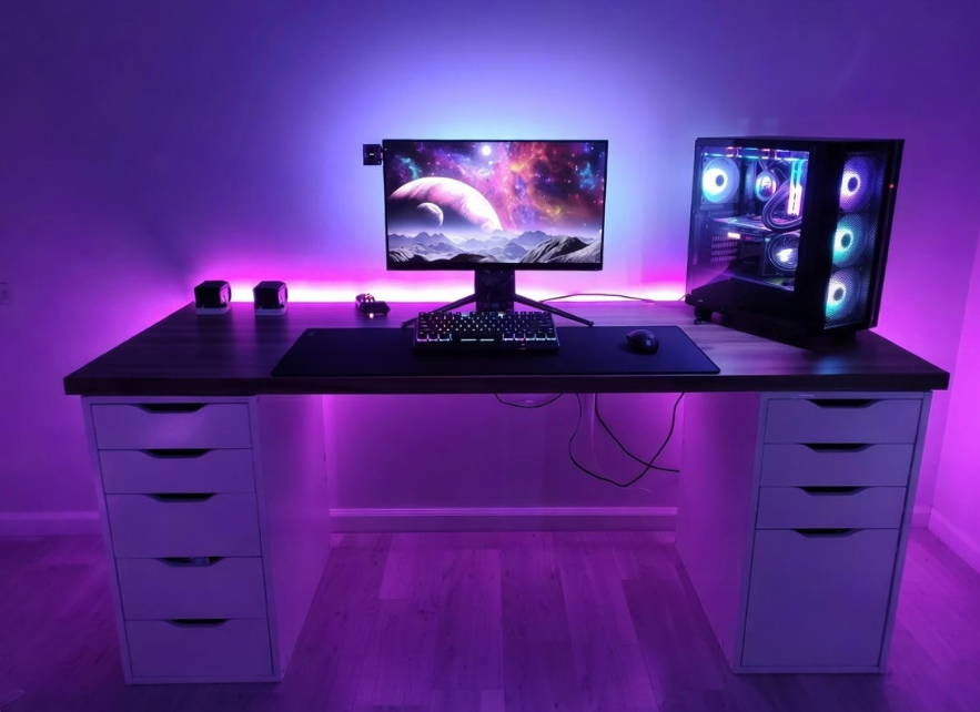 Modern gaming desk setup with computer monitor, keyboard, and RGB lighting.